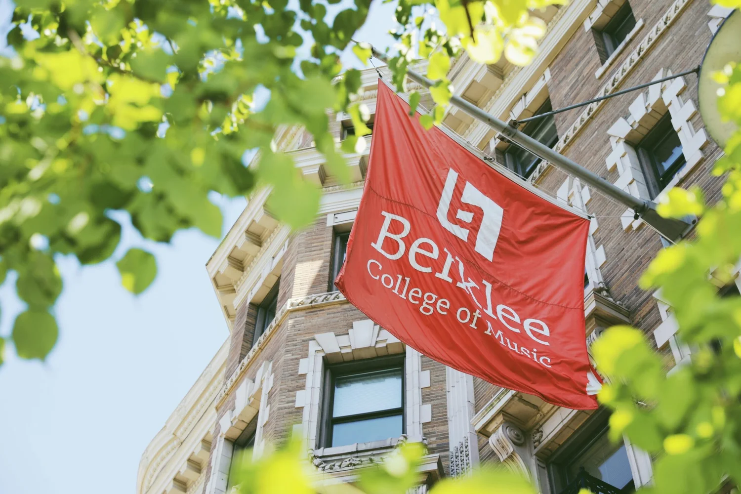 La bandera roja de Berklee College of Music en un edificio de ladrillo de Boston